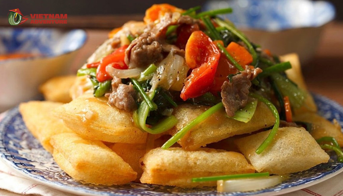 A plate of crispy fried pho with a bowl of flavorful dipping sauce