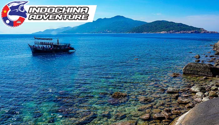 Boat sailing on clear blue waters near Cham Islands in Vietnam.