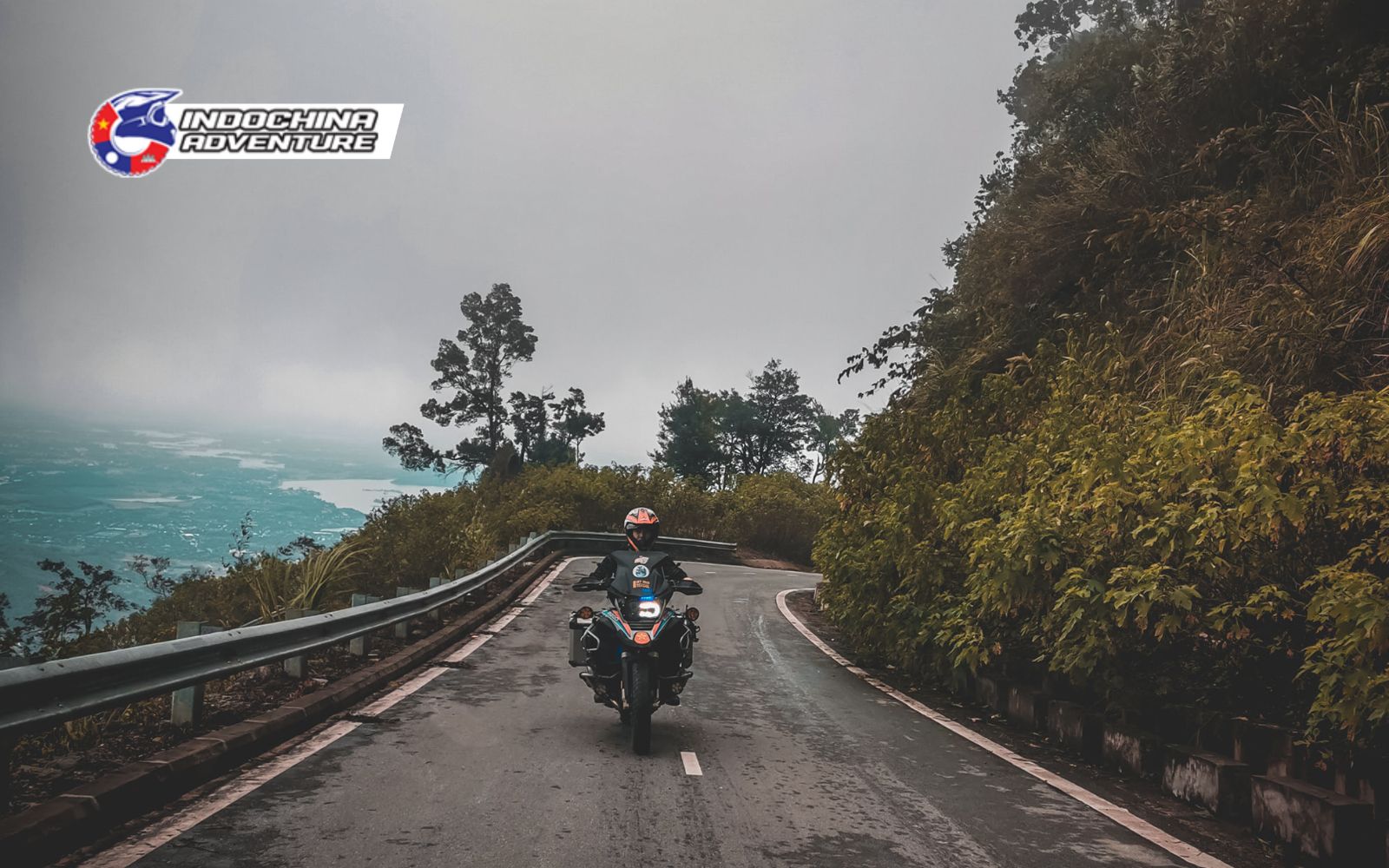 Motorcyclist stopping at Hai Van Pass viewpoint, overlooking the sea and mountains