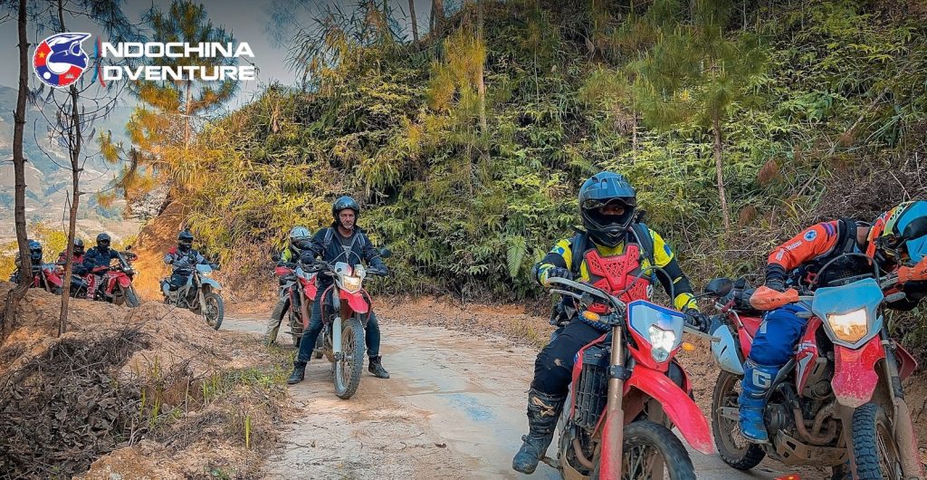 Dirtbike rider on a muddy forest trail during an offroad motorbike tour in Vietnam
