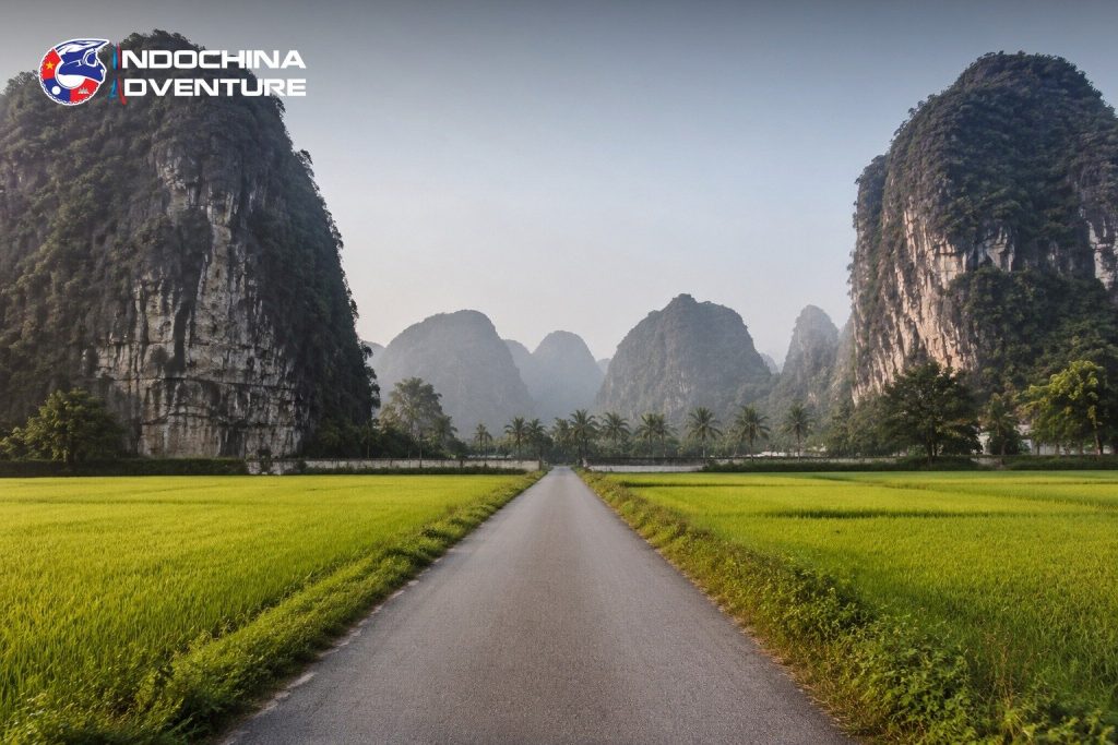 Narrow road between limestone karst and rice fields on a Ninh Binh motorbike tour