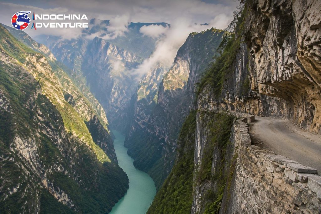Narrow road cut into a cliff above a deep canyon on the northern Vietnam motorbike loop